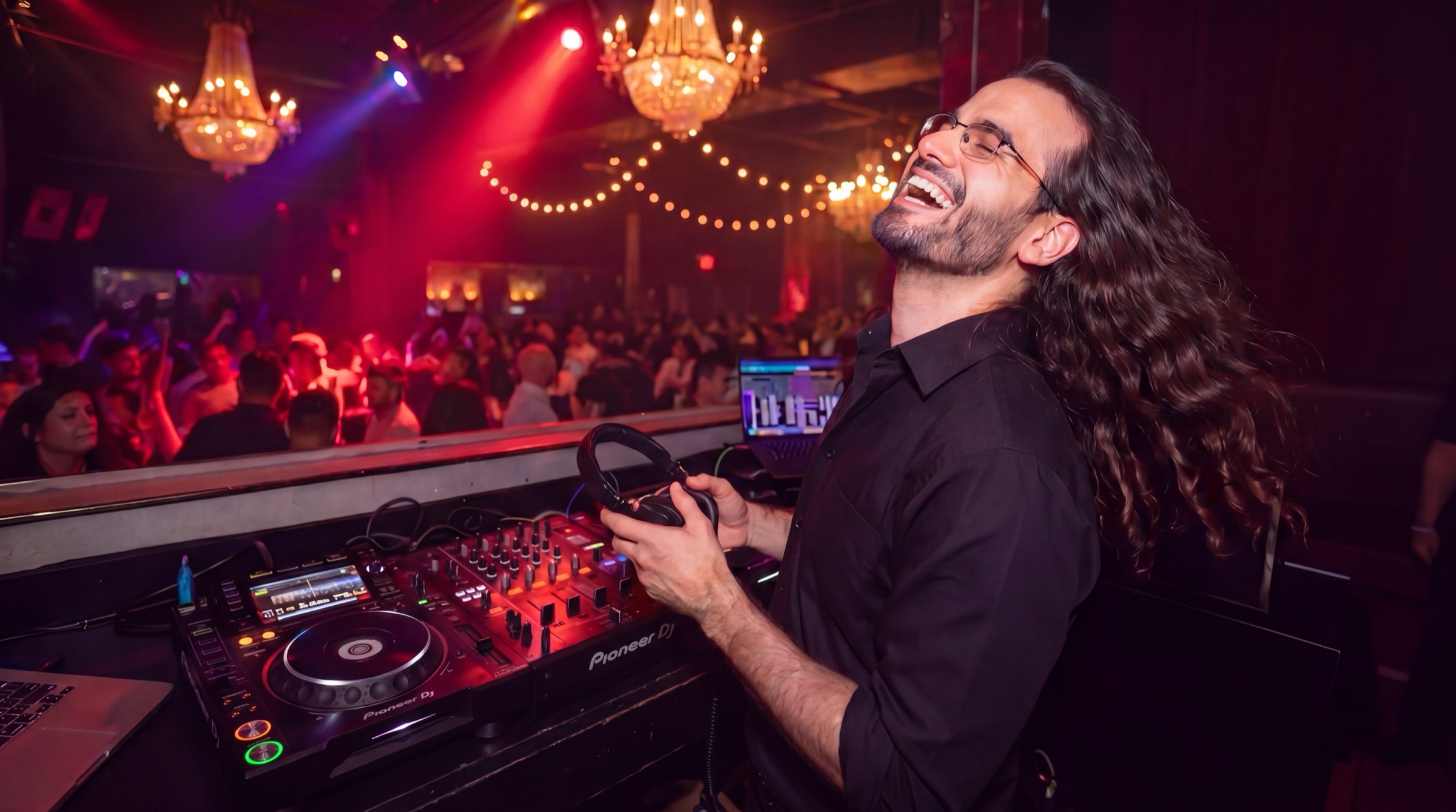 el-eje laughing behind the decks in a chandelier ballroom